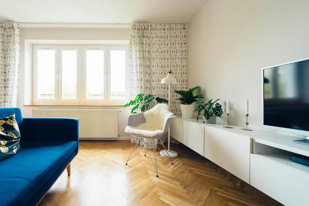 Bright living room with herringbone floorboards and a large window