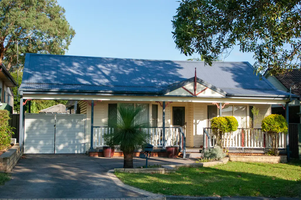 A weatherboard Australian bungalow with a verandah and a corrugated roof