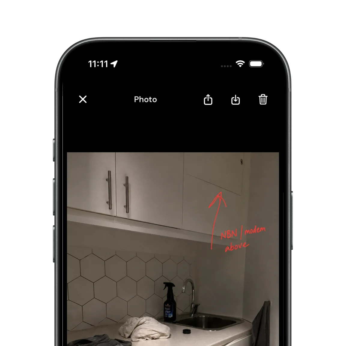 A maintenance photo open in Girilang markup on iPhone, with an arrow and a handwritten note drawn over a kitchen wall
